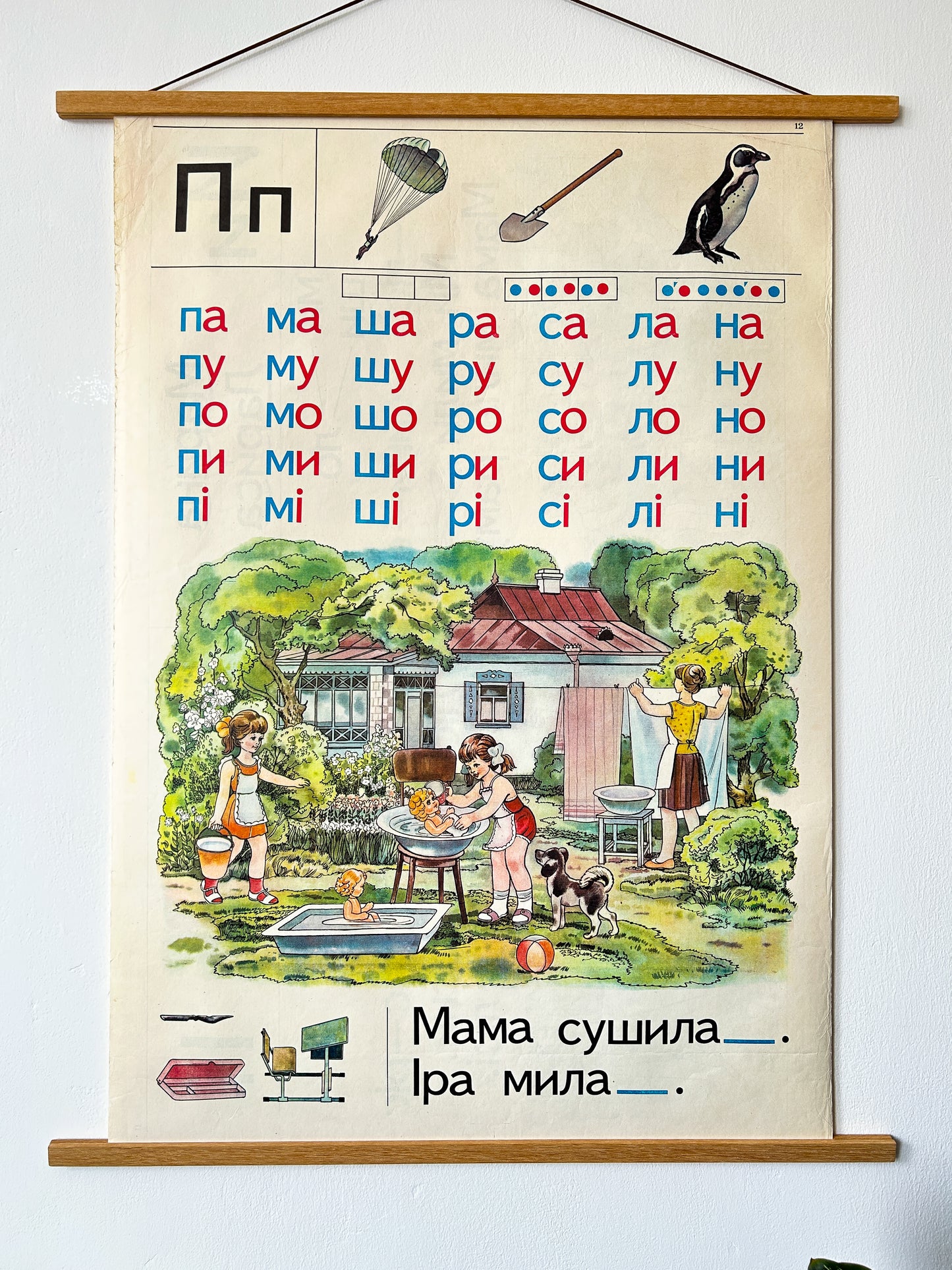 Ukrainian vintage alphabet poster letter P illustration: two girls bathing dolls in the garden with dog nearby, mum hanging linen with a house at the background