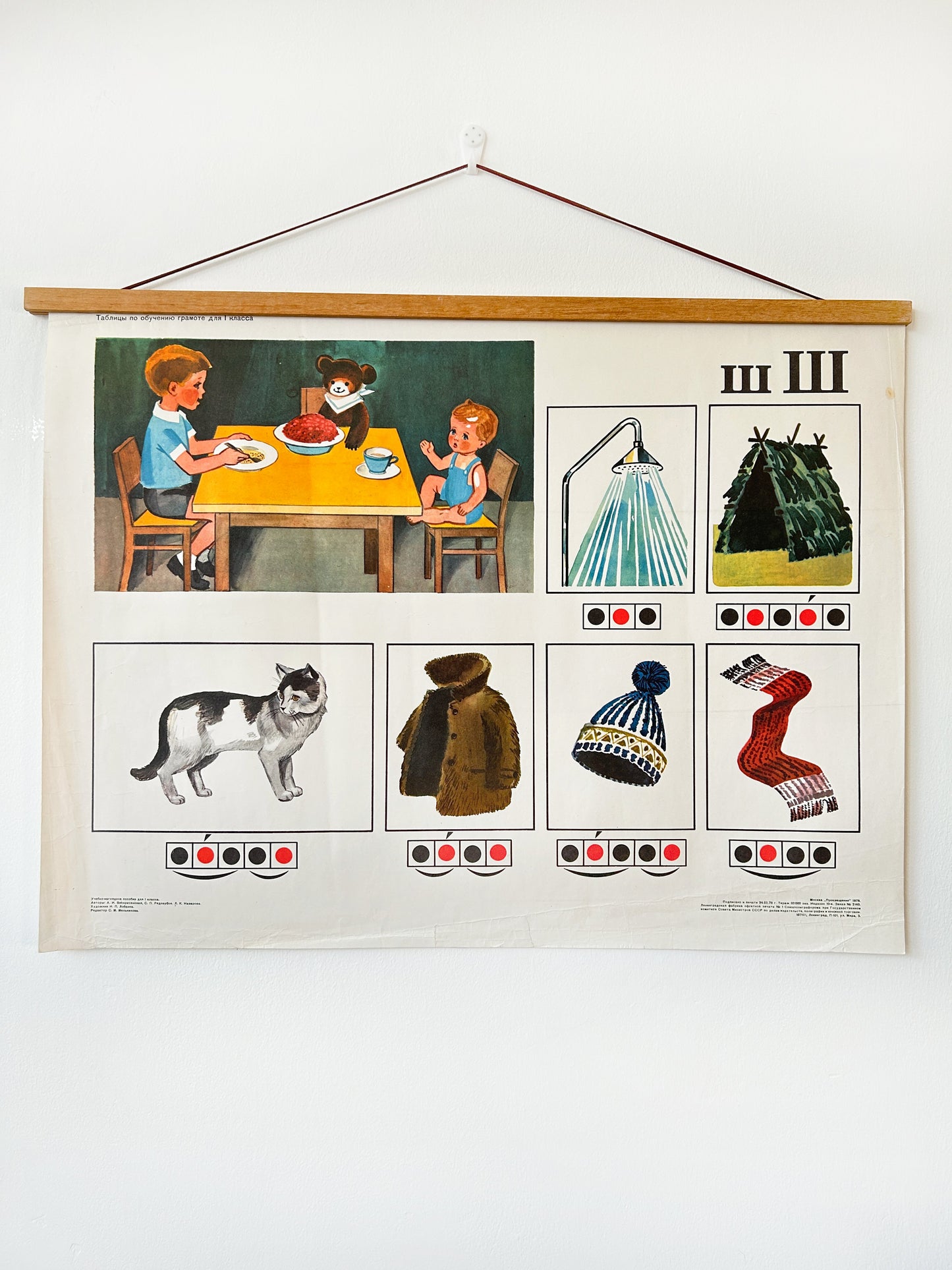 An original Soviet vintage phonetic Russian alphabet poster printed in Moscow in 1978, with colourful illustrations of a cat, a boy eating with a doll and a teddy bear, a shower, a hat, a scarf, a fur coat and a hut.