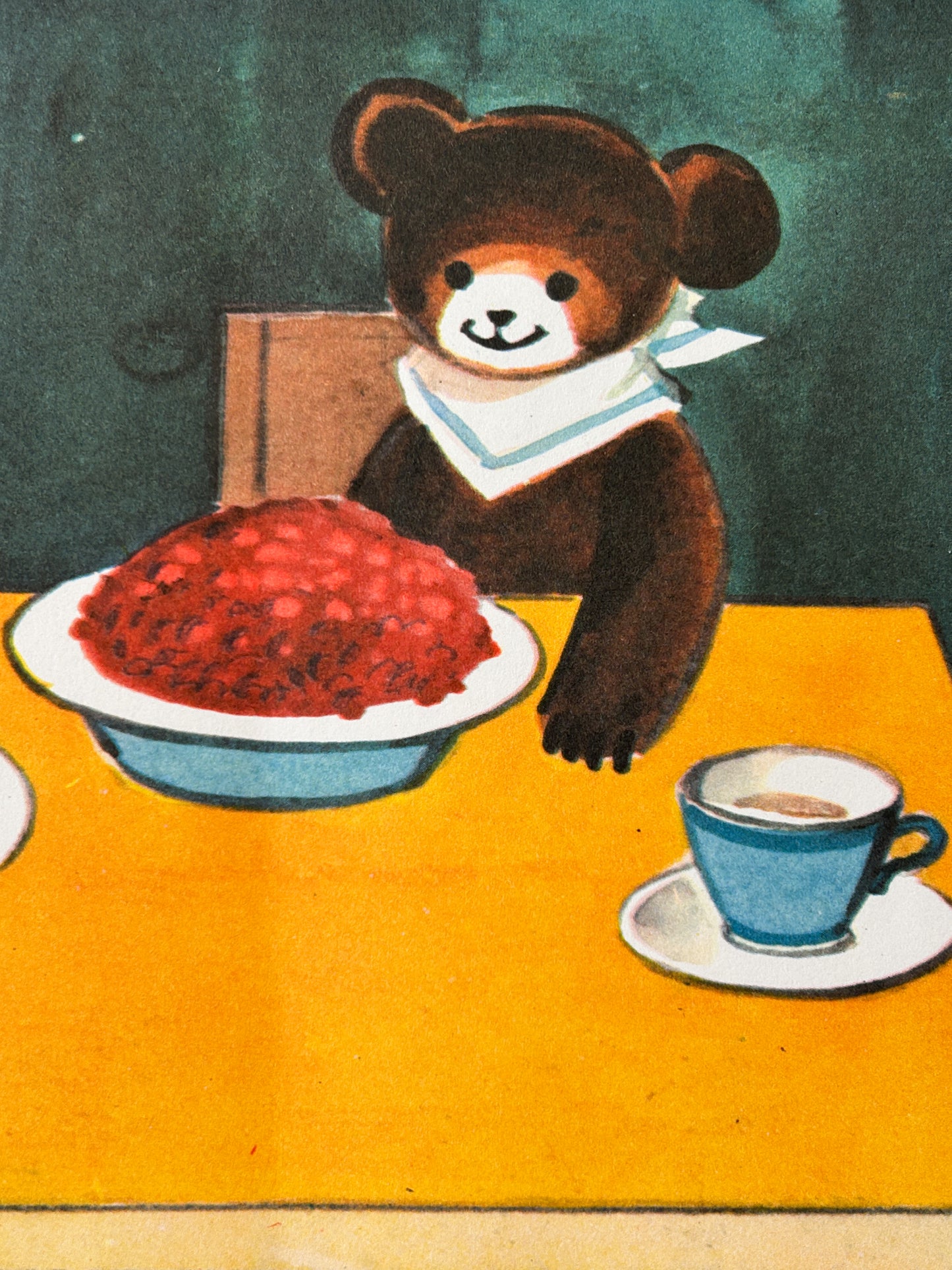 USSR vintage nursery poster detiail - an illustration of a brown teddy bear wearing a white sailor collar, seated at a yellow table with a bowl of red jam or fruit spread in front, a blue cup on a saucer, and a dark green background.
