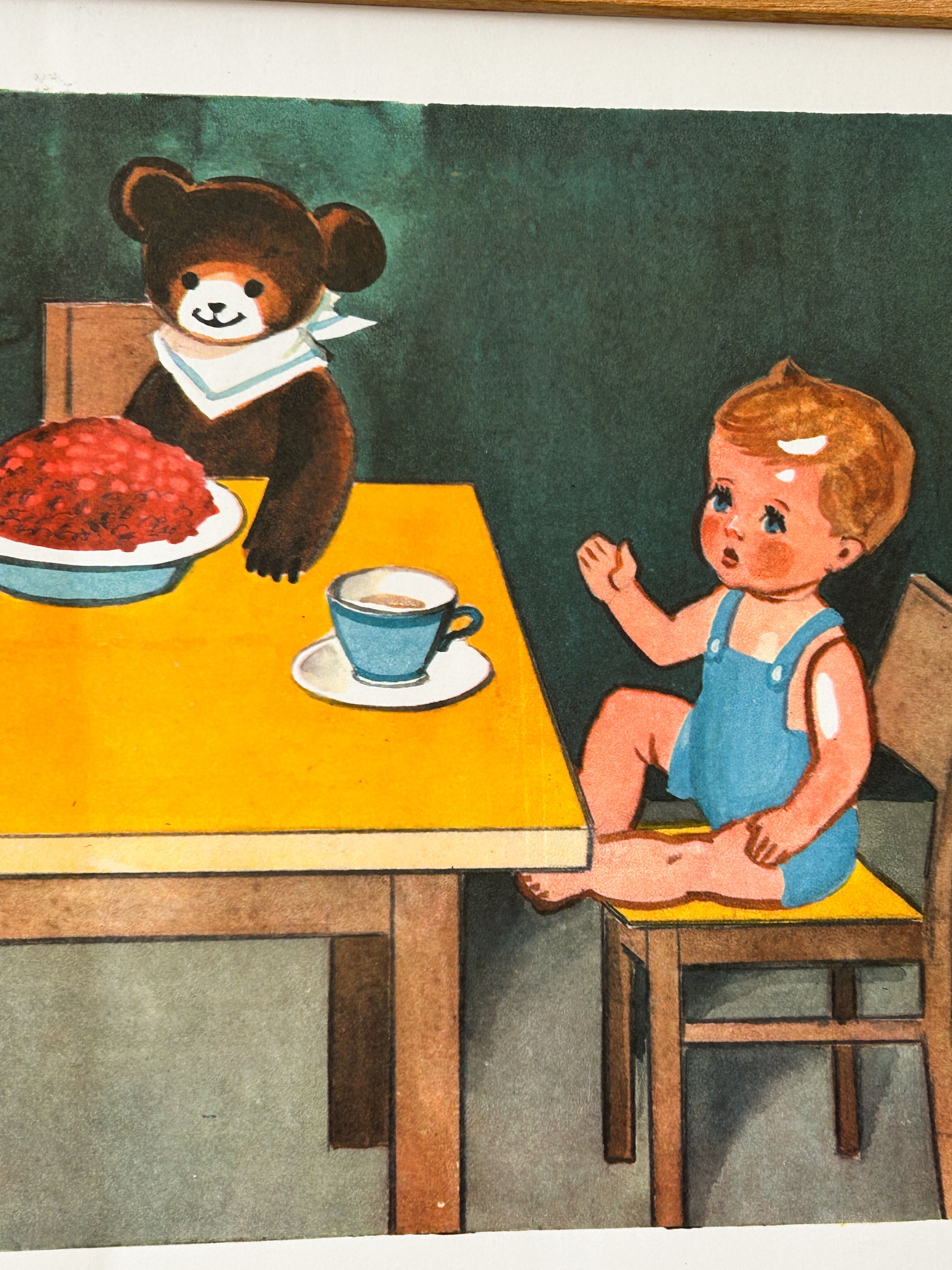 USSR vintage educational nursery poster detail - a  watercolour illustration of a doll in blue overalls sitting at a table with a cup, facing a teddy bear wearing a white bib with a large plate of red food on the other side.