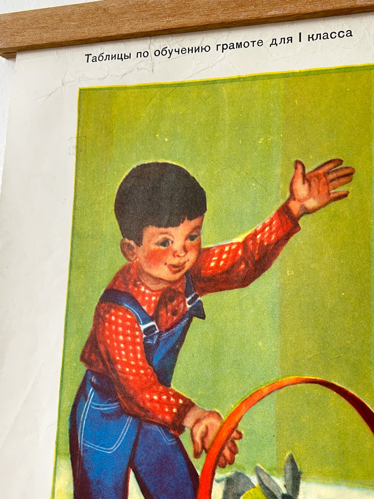 A vintage Russian school workbook page showing a child in blue overalls and a red polka-dot shirt waving, with black Cyrillic text at the top reading 'Tables for learning grammar for 1st class'.