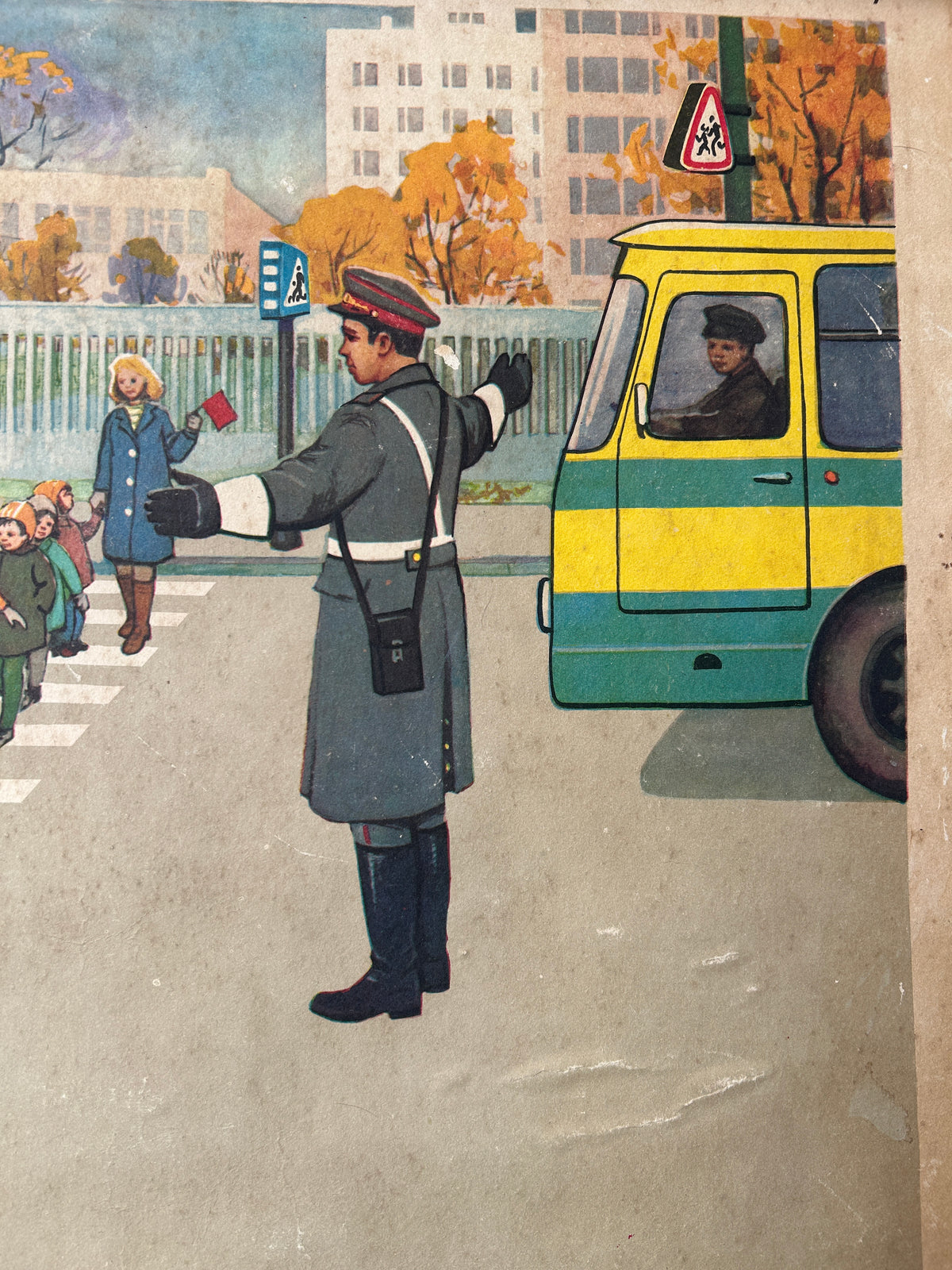 USSR vintage road safety poster detail:  illustration of a traffic police officer directing pedestrians at a crosswalk next to a yellow and green bus, with children waiting and buildings in the background.