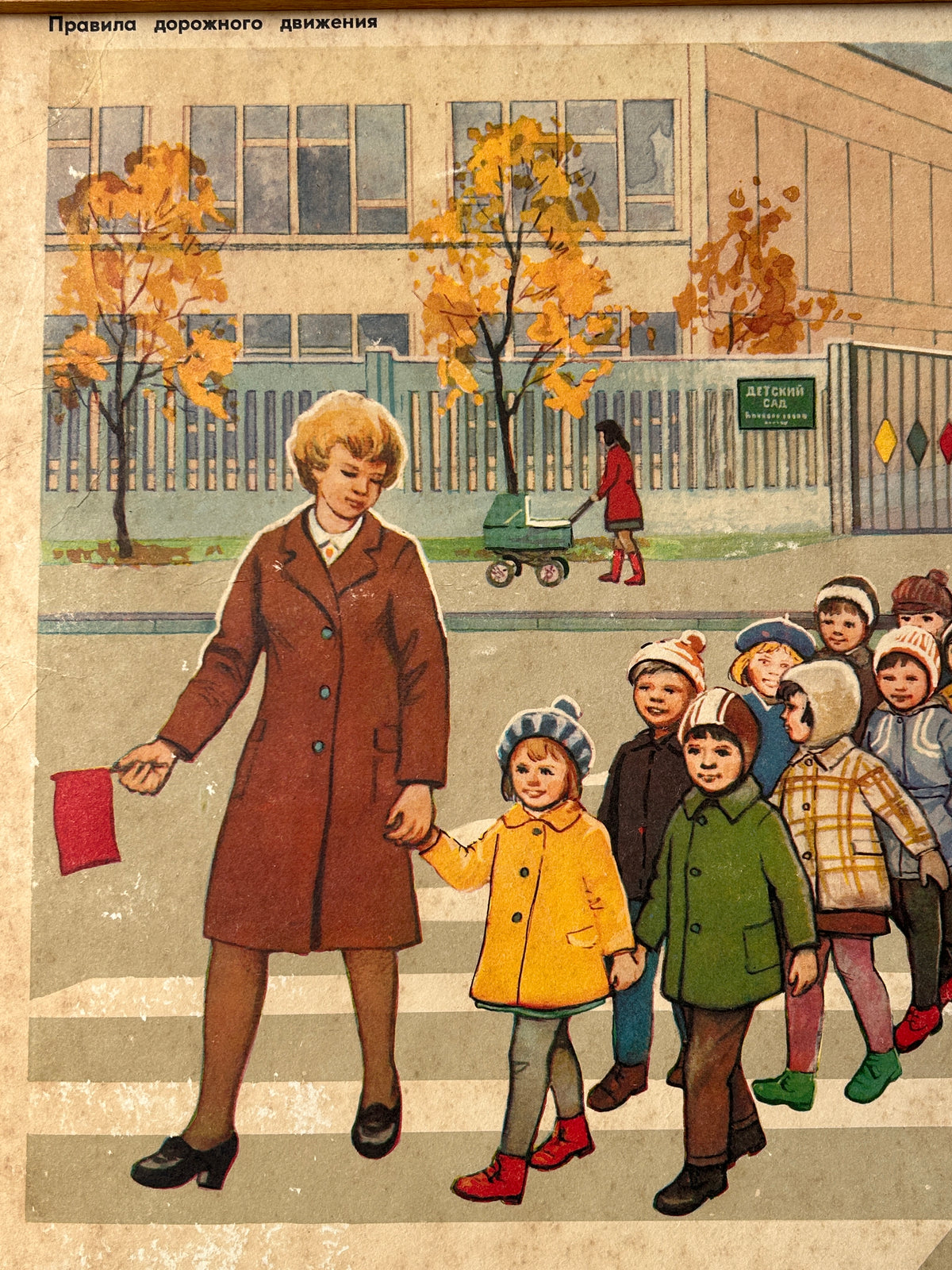 USSR vintage road safety poster detail: illustration showing a teacher in a brown coat crossing a street with children, with trees in autumn and a building in the background. 