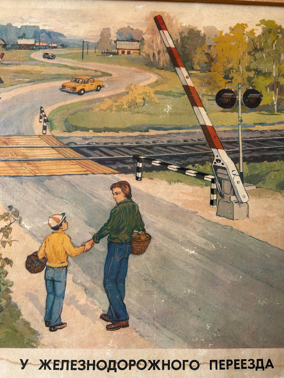 USSR vintage road safety poster detail: illustration depicting a railway crossing with a lowered red-and-white barrier, two people standing near the tracks, a road with a car in the background, and Cyrillic text at the bottom.