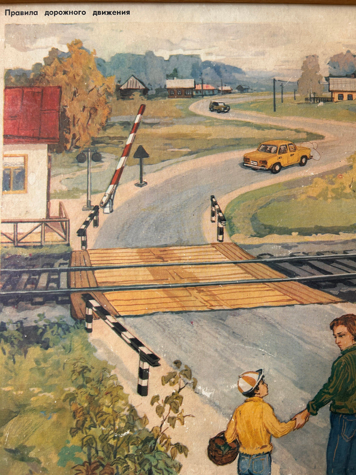 USSR vintage road safety poster detail:  illustrated scene showing a railroad crossing with lowered barriers, a yellow car on a curved road, houses, trees, and two people in the foreground holding hands. Russian text appears at the top.
