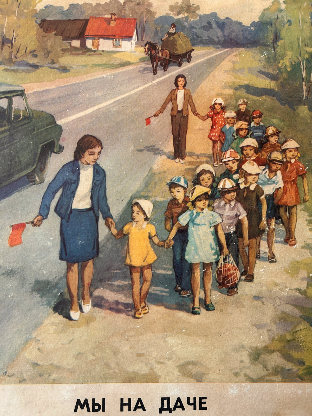 Detail of a vintage USSR illustrated road safety poster: a countryside scene showing a group of children and teachers walking along a country road, with a horse-drawn carriage in the distance, houses, trees, and a car on the left. Russian text appears at the bottom.