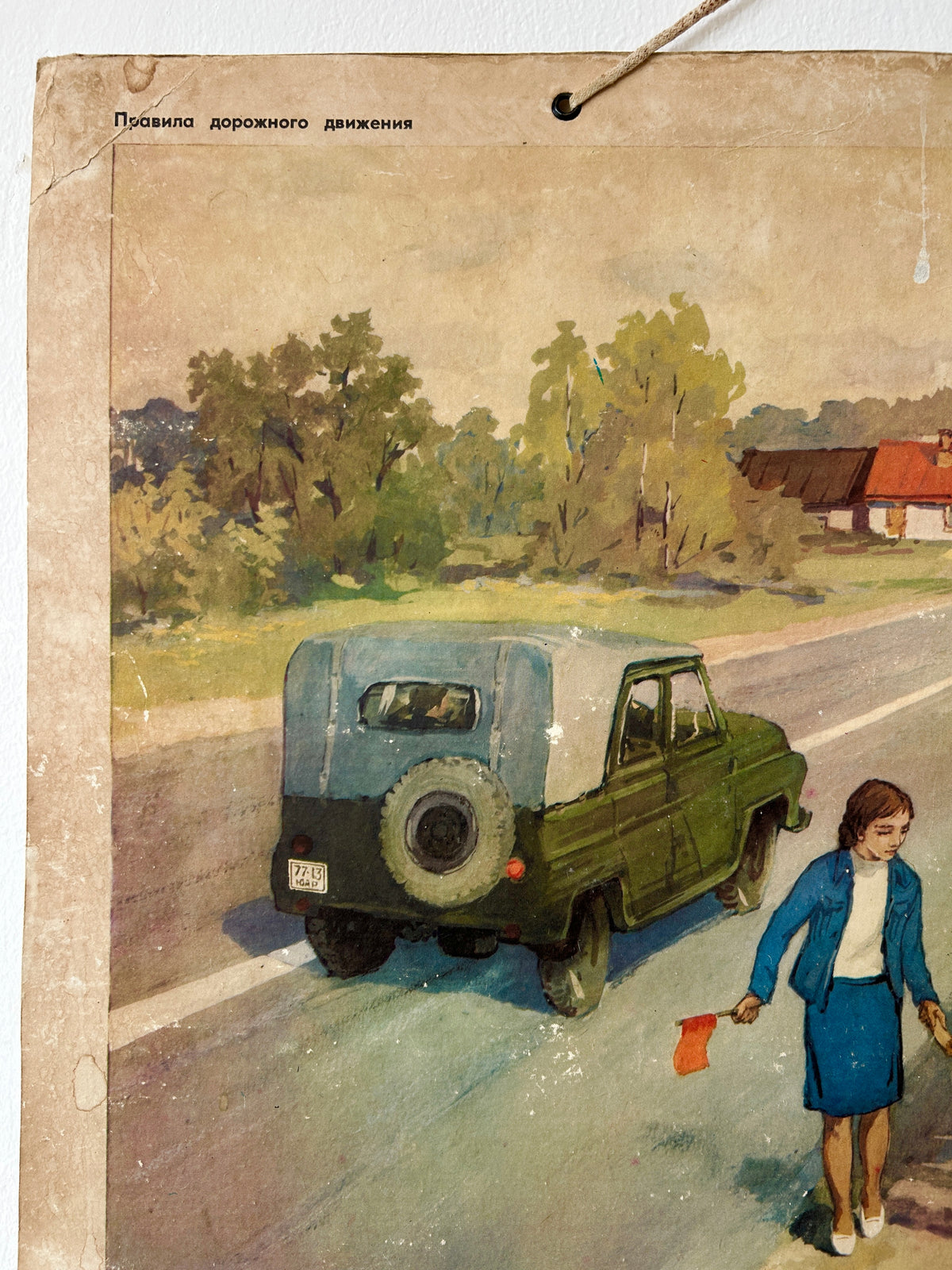 Detail of a vintage USSR illustrated road safety poster: a countryside scene showing a teacher walking along a country road, with a military car in the background.
