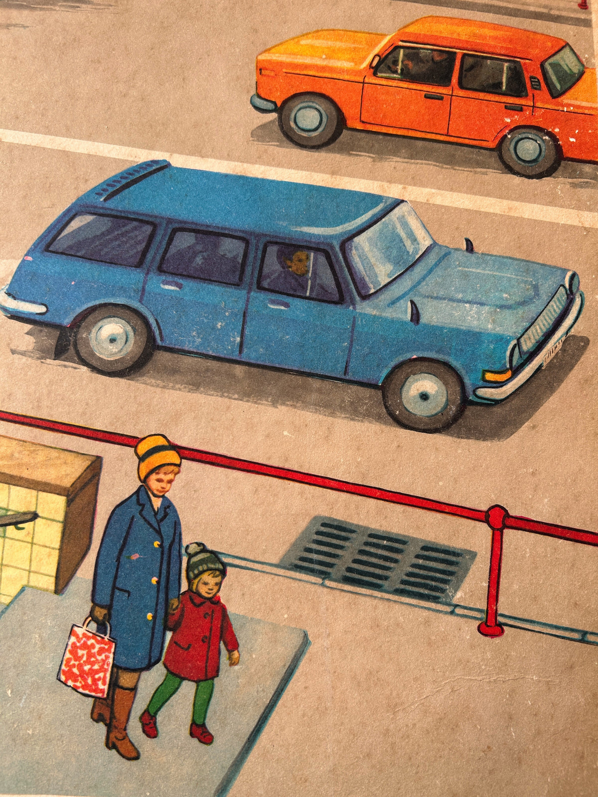Detail of a vintage USSR illustrated road safety poster: a street scene showing a parent and a child coming out of an underground pedestrian crossing with cars at the background.