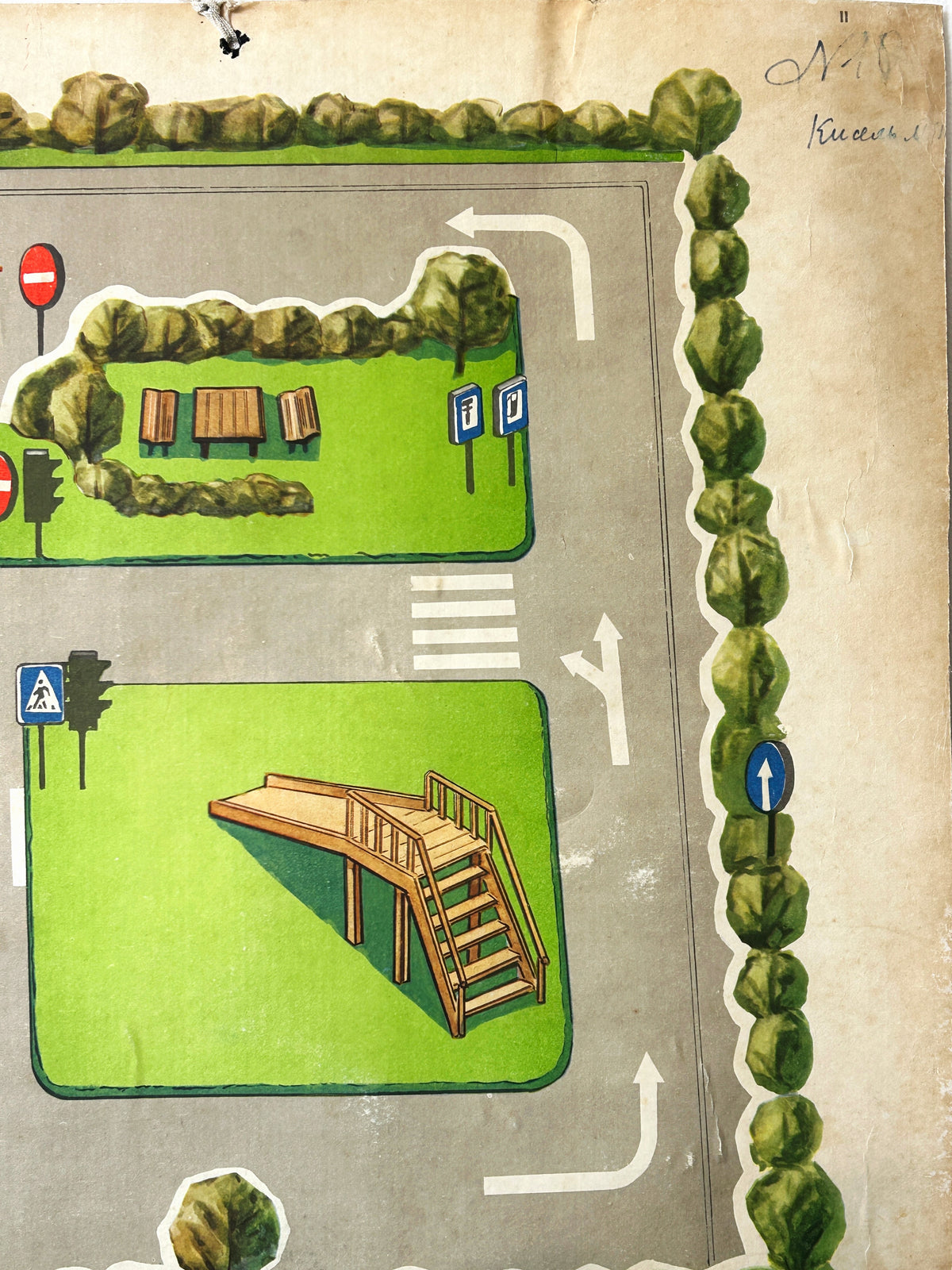 A close-up of a colourful USSR vintage children's road safety poster showing a street scene with a grey road, a playground with a slide, crosswalks, traffic lights, green grass areas with a table and benches.