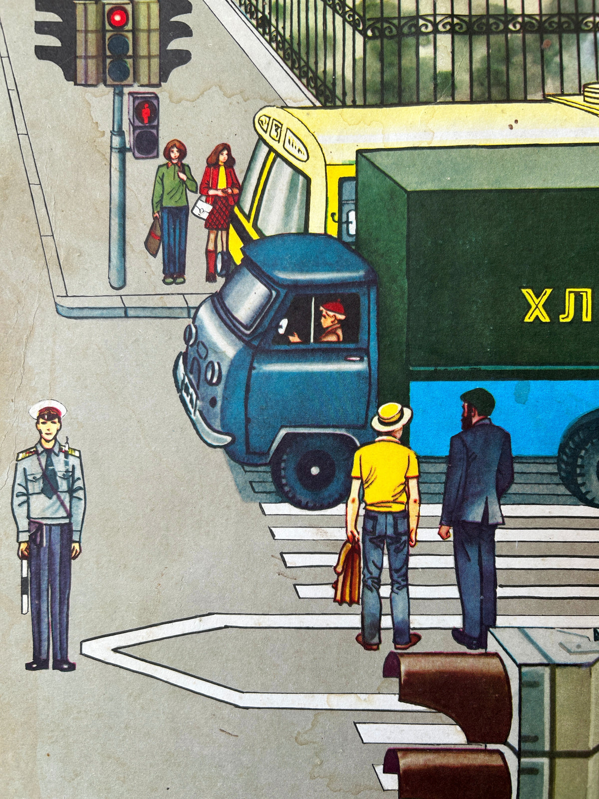 Close-up detail of a Soviet vintage road safety poster: a street scene illustration showing pedestrians at a crosswalk, a yellow and green bus, a blue Bread delivery truck and traffic lights. 
