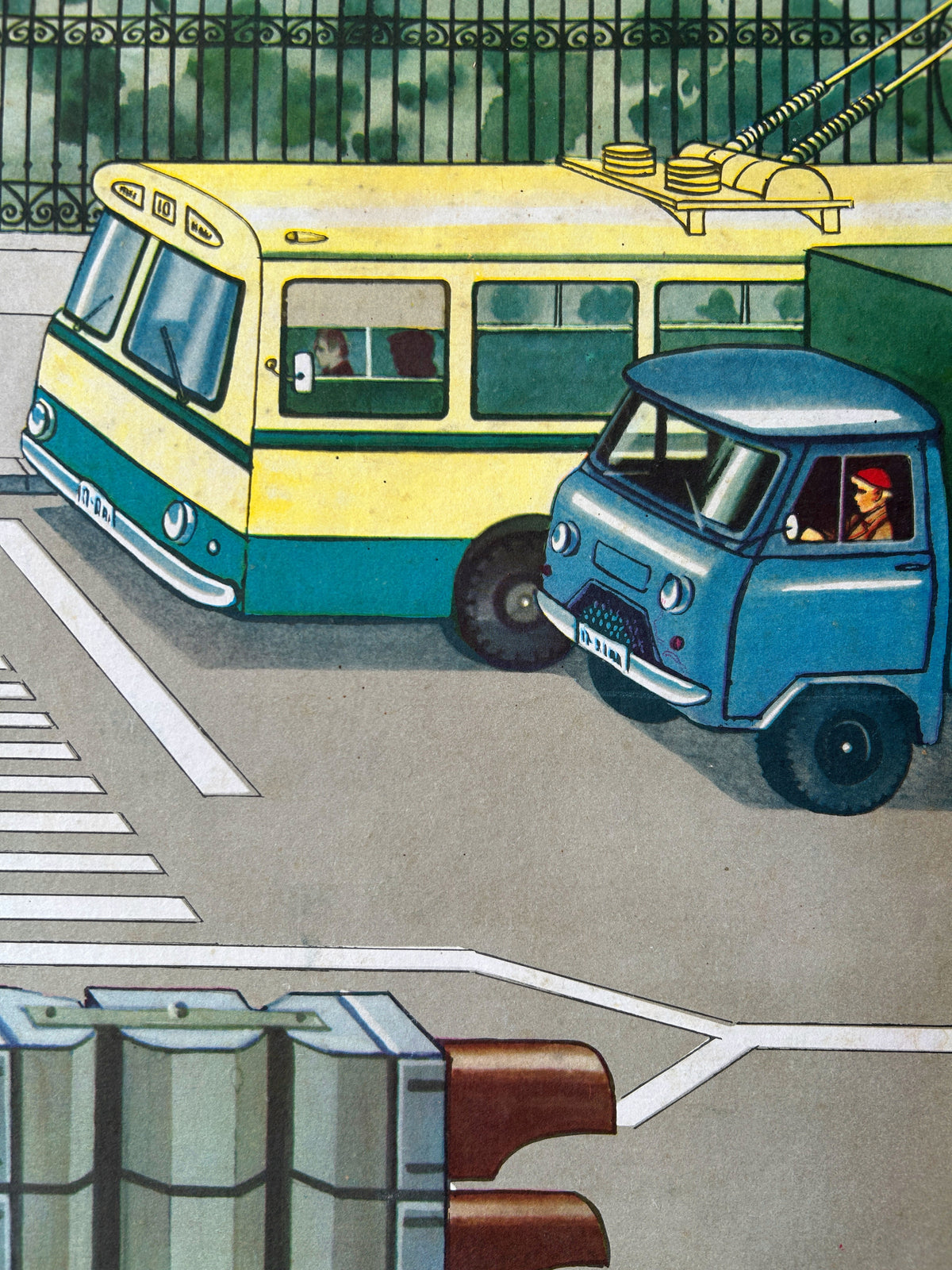 Close-up detail of a USSR vintage road safety poster illustrating a street scene: a yellow and teal trolleybus alongside a small blue truck on a street, with a fence and greenery in the background.