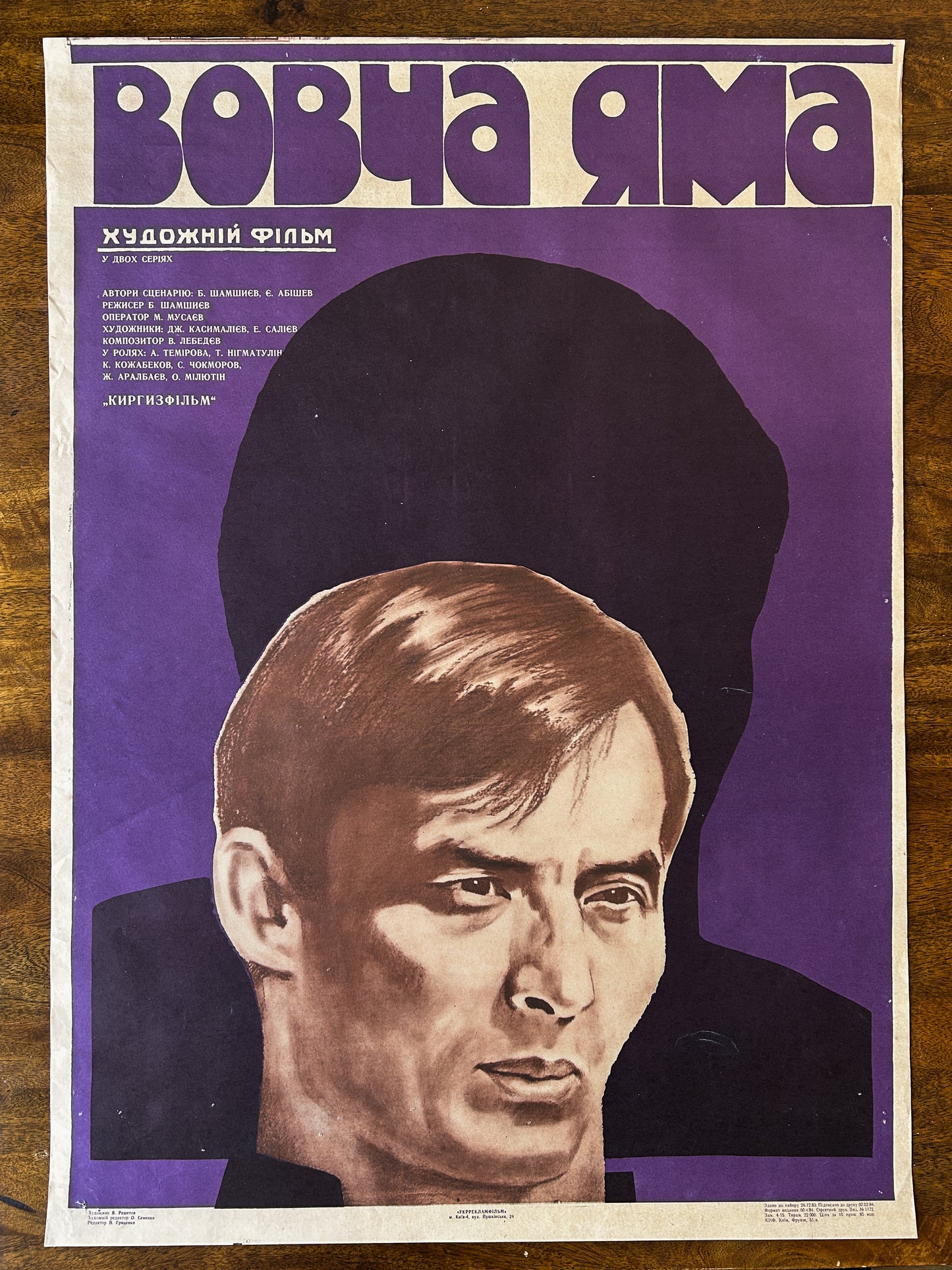 Soviet vintage movie poster with a stylized portrait of a man on a purple background and Ukrainian Text 