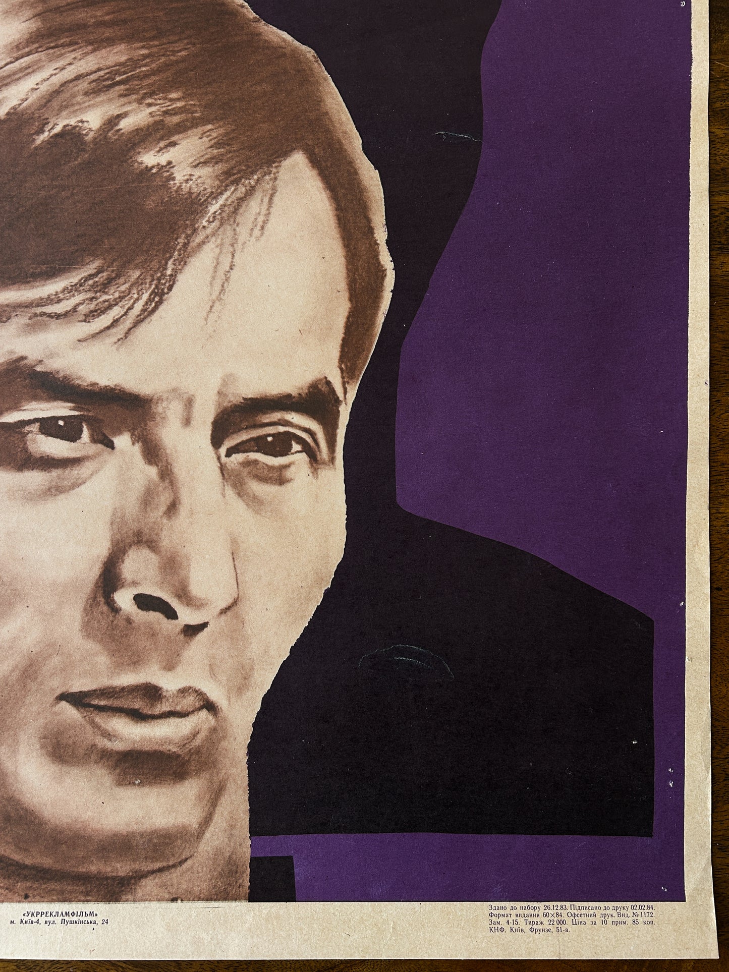 detail of a Soviet vintage film poster showing a man's face on a purple background and print details 1983