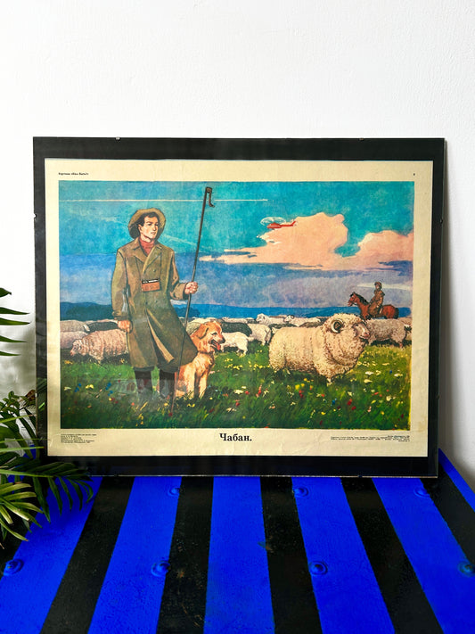 A framed Soviet vintage art print depicting a shepherd with a dog and sheep under a blue sunset sky, with a helicopter flying above and a horse in the background.